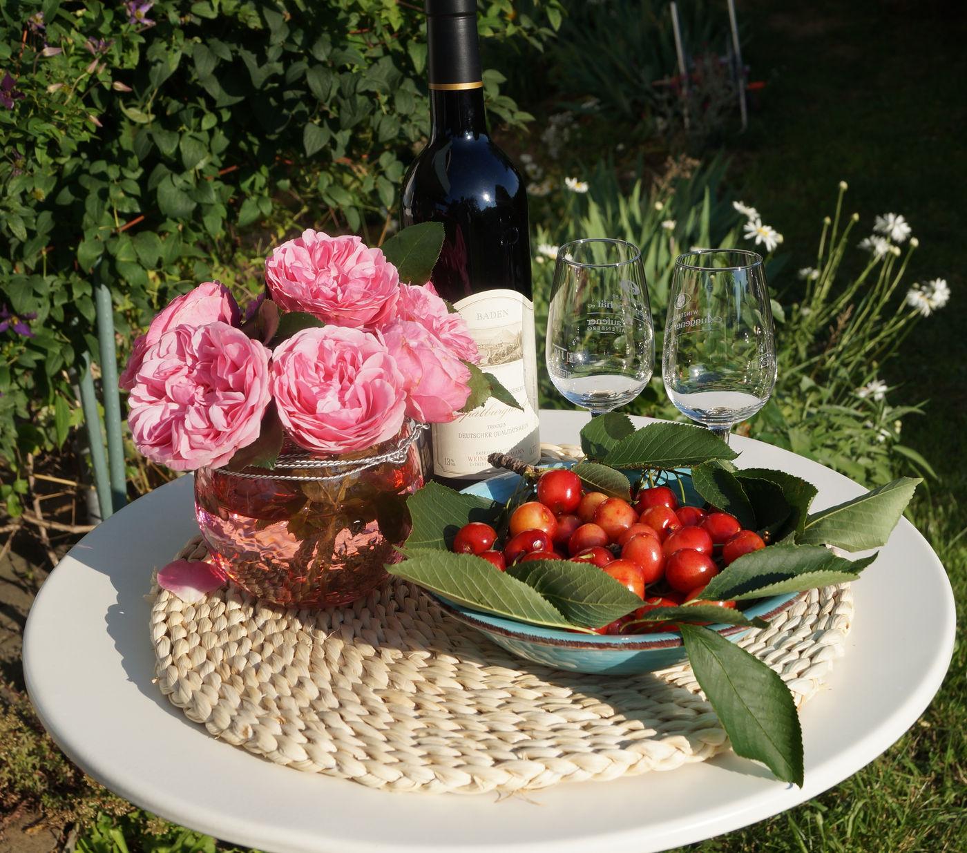 Willkommenstisch im Garten mit Rosen, Wein und Kirschen
